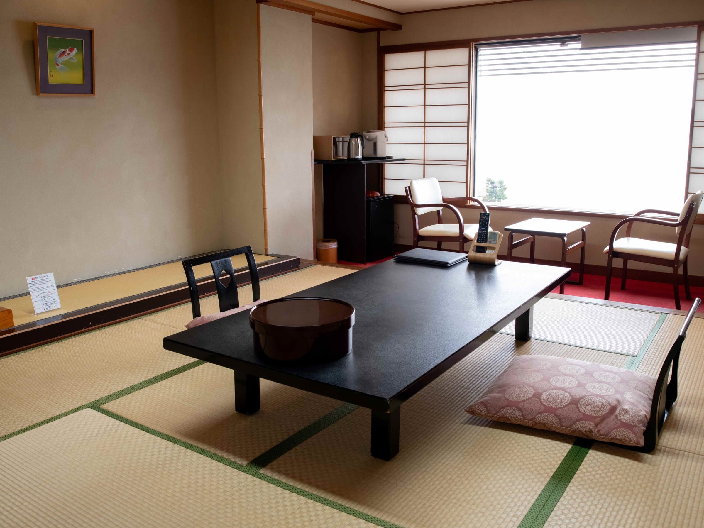 Spacious tatami guest room at Hotel Miyarikyu with a low black table, floor cushions and a bright bay-view window