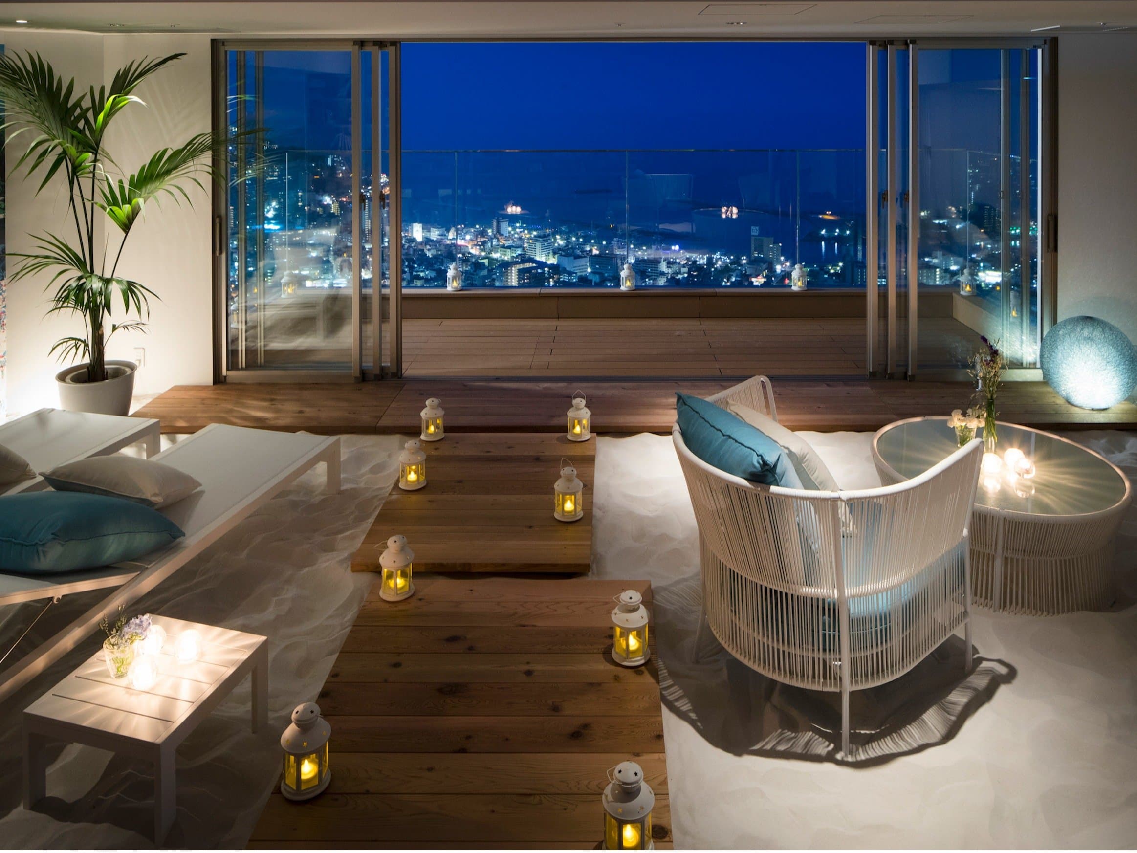 Lantern-lit sand-floor lounge at Risonare Atami overlooking the Atami city night skyline