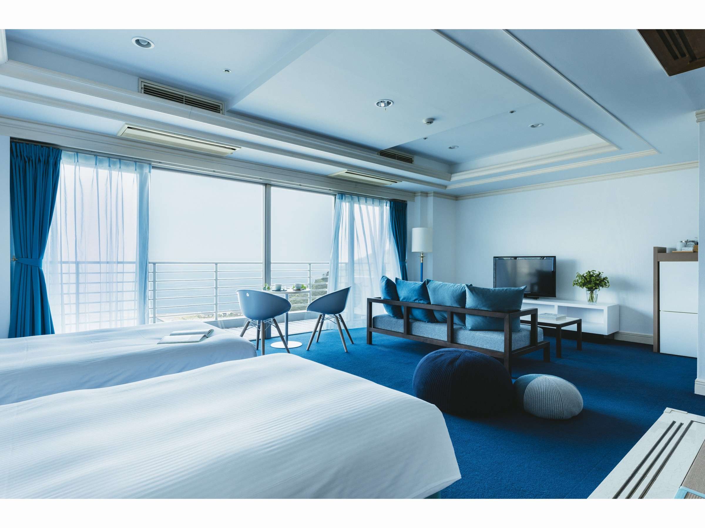 Spacious blue ocean-view guest room at Risonare Atami with twin beds and a sea-facing balcony