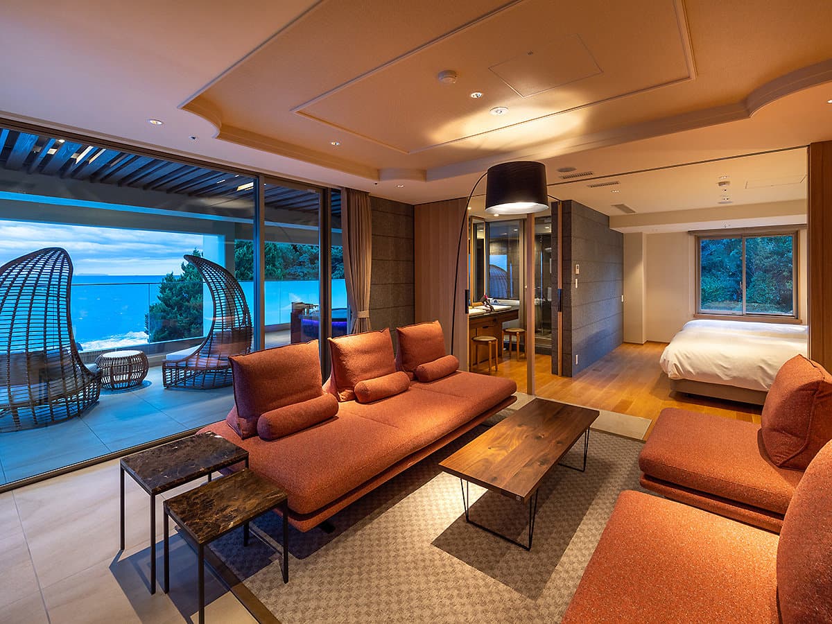Spacious sea-view suite with living lounge and bedroom and hanging chairs facing the ocean at Hama no Yu
