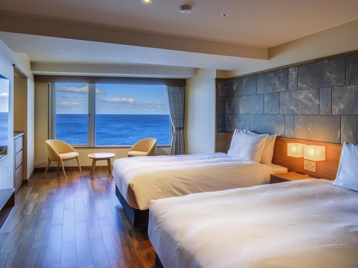 Twin guest room with a wide window framing the Pacific Ocean at Hama no Yu, Inatori Onsen