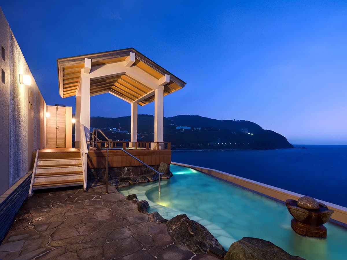 Rooftop rotenburo with a wooden gazebo and clifftop sea view at twilight at Hama no Yu, Izu
