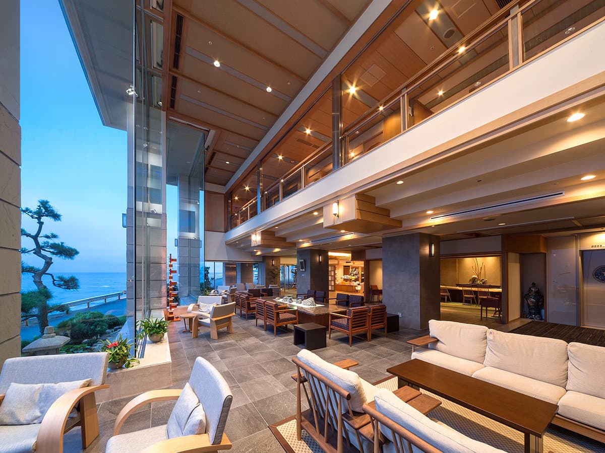 Open lobby lounge with high ceilings and sea-facing windows at Hama no Yu in Izu