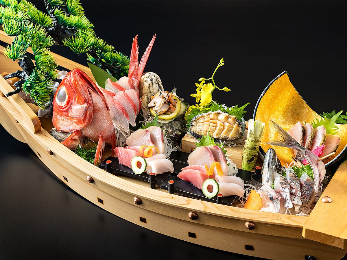 Seafood kaiseki served on a wooden boat platter with whole kinmedai snapper and sashimi at Hama no Yu