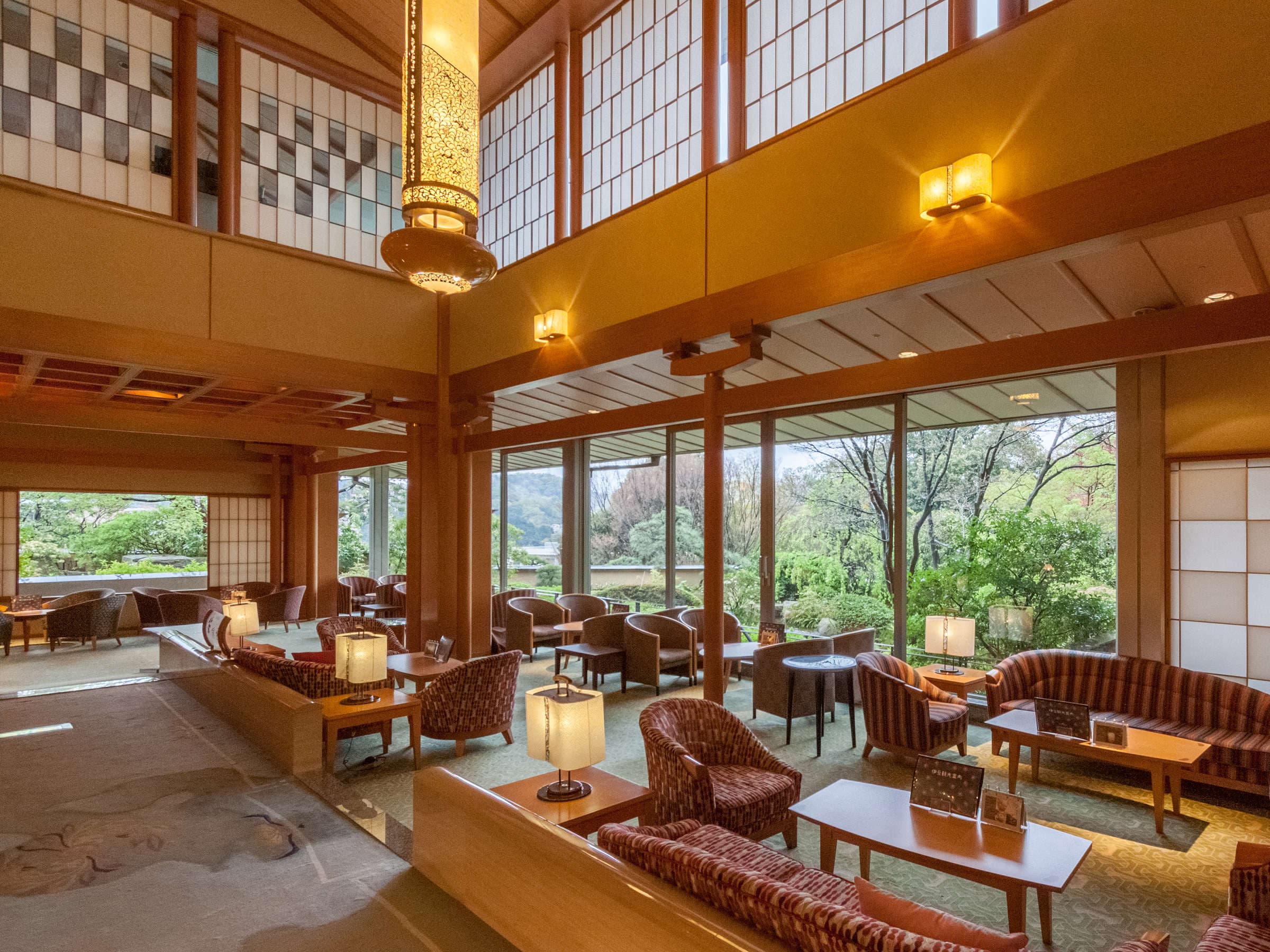 Open lobby lounge with leather chairs, hanging lantern and garden-view windows at Seizan Yamato, Izu