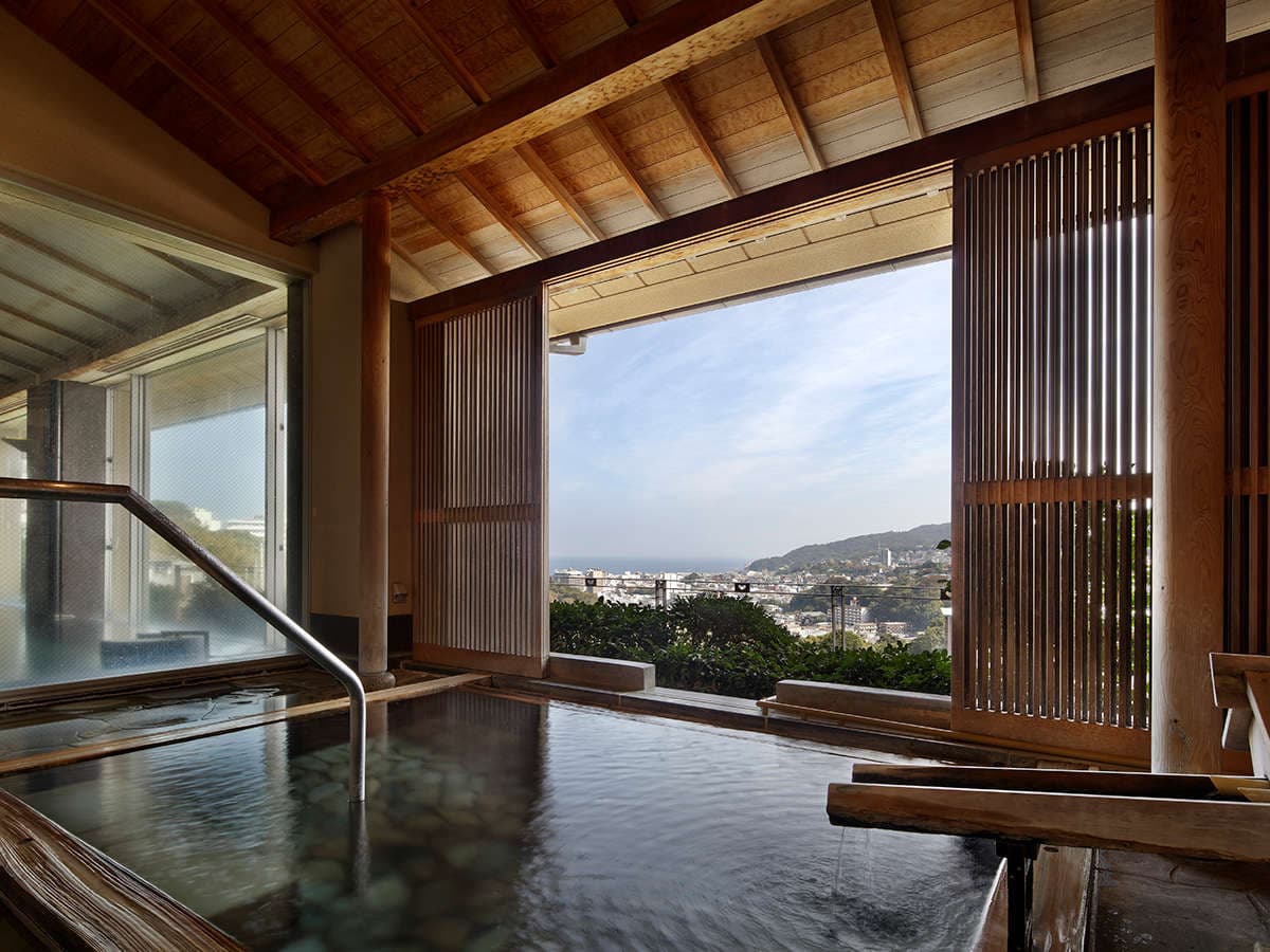 Indoor hot-spring bath with a wide window overlooking the town and coast of Ito at Seizan Yamato