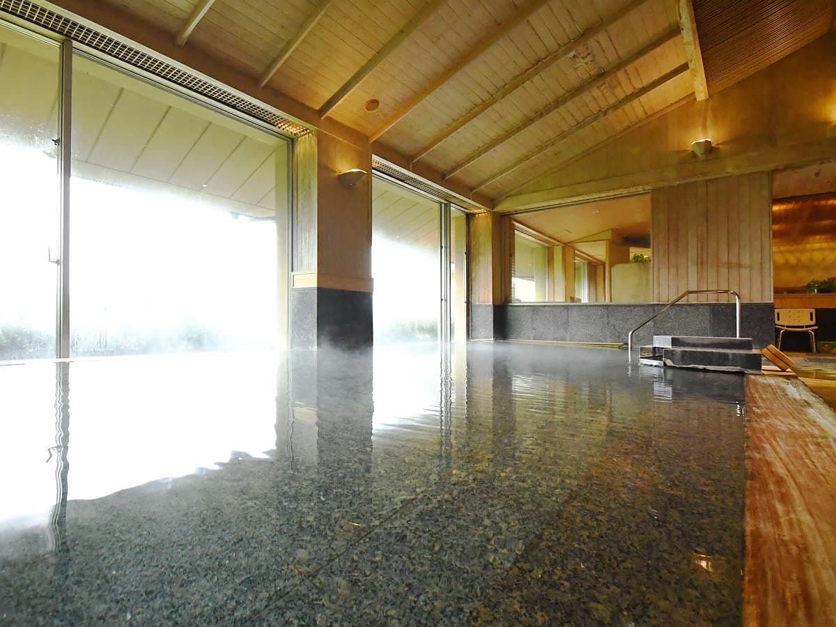 Large indoor hot-spring bath with steam rising and wide windows at Seizan Yamato, Ito Onsen