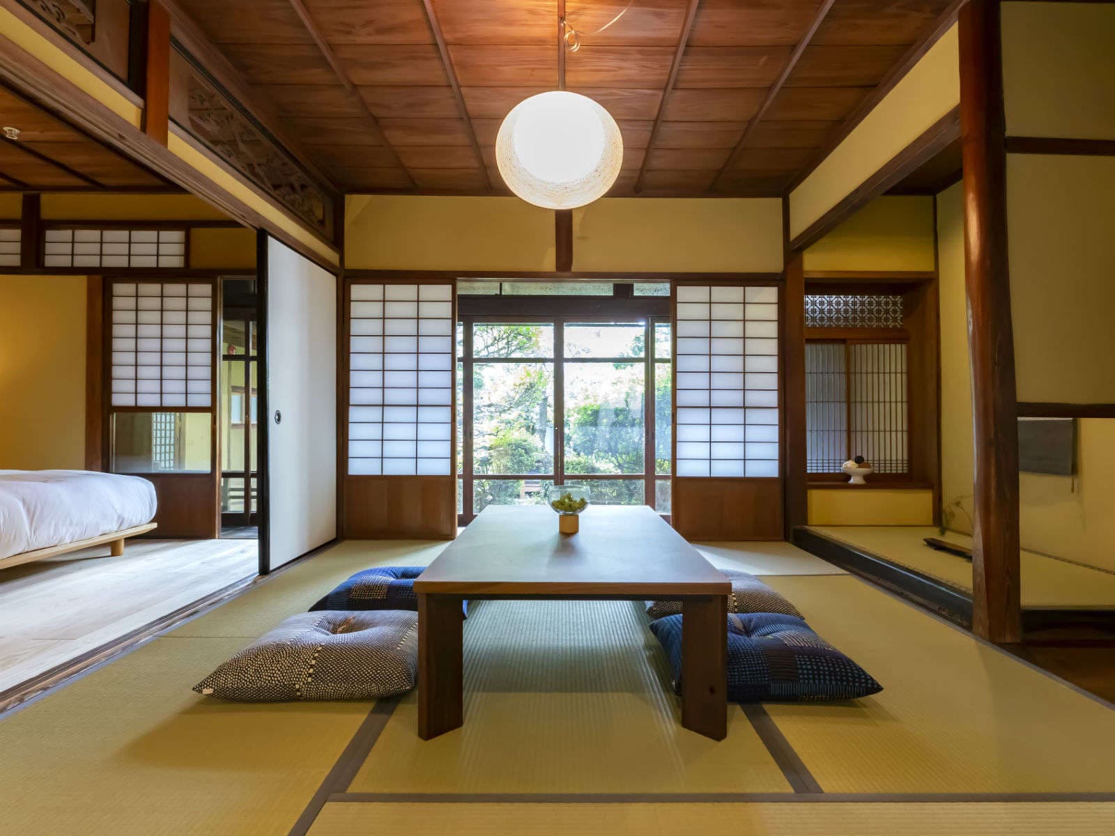 Spacious tatami guest room at Kaze no Naramachi with a low wooden table, floor cushions and shoji screens opening to a garden
