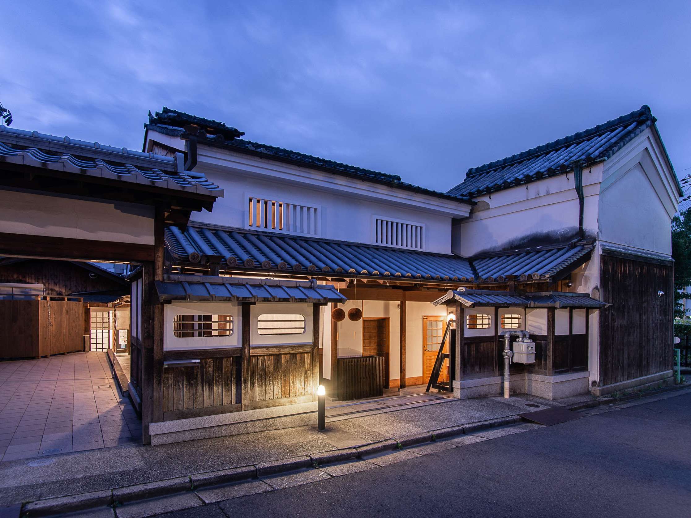 Kaze no Naramachi exterior at dusk, the renovated Meiji-era sake brewery machiya facade lit by a lantern in the Naramachi historic district