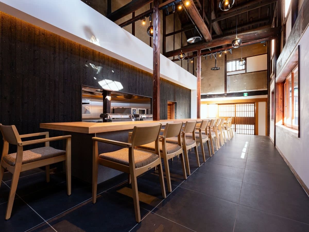 Lounge and dining counter inside the converted sake brewery at Kaze no Naramachi with charred-cedar walls and exposed beams