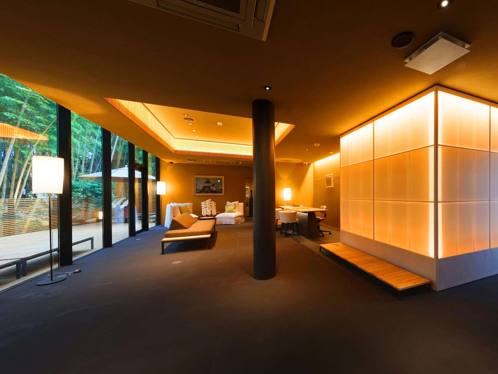 Lobby lounge at Koto no Niwa with illuminated lantern-cube, floor lamps and bamboo garden through glass walls