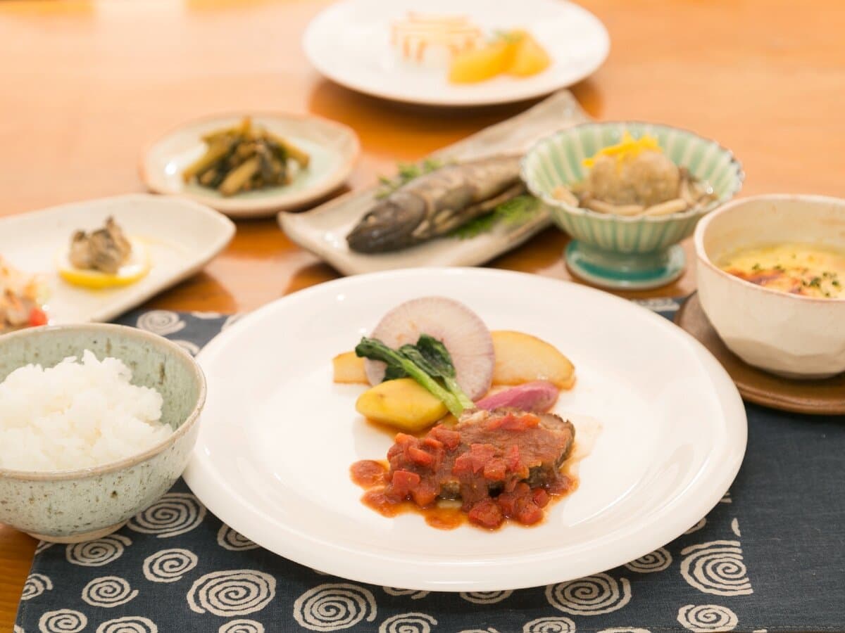 Dinner course at Ryokan Mokuzin featuring a tomato-sauced main dish, rice and assorted small Japanese plates