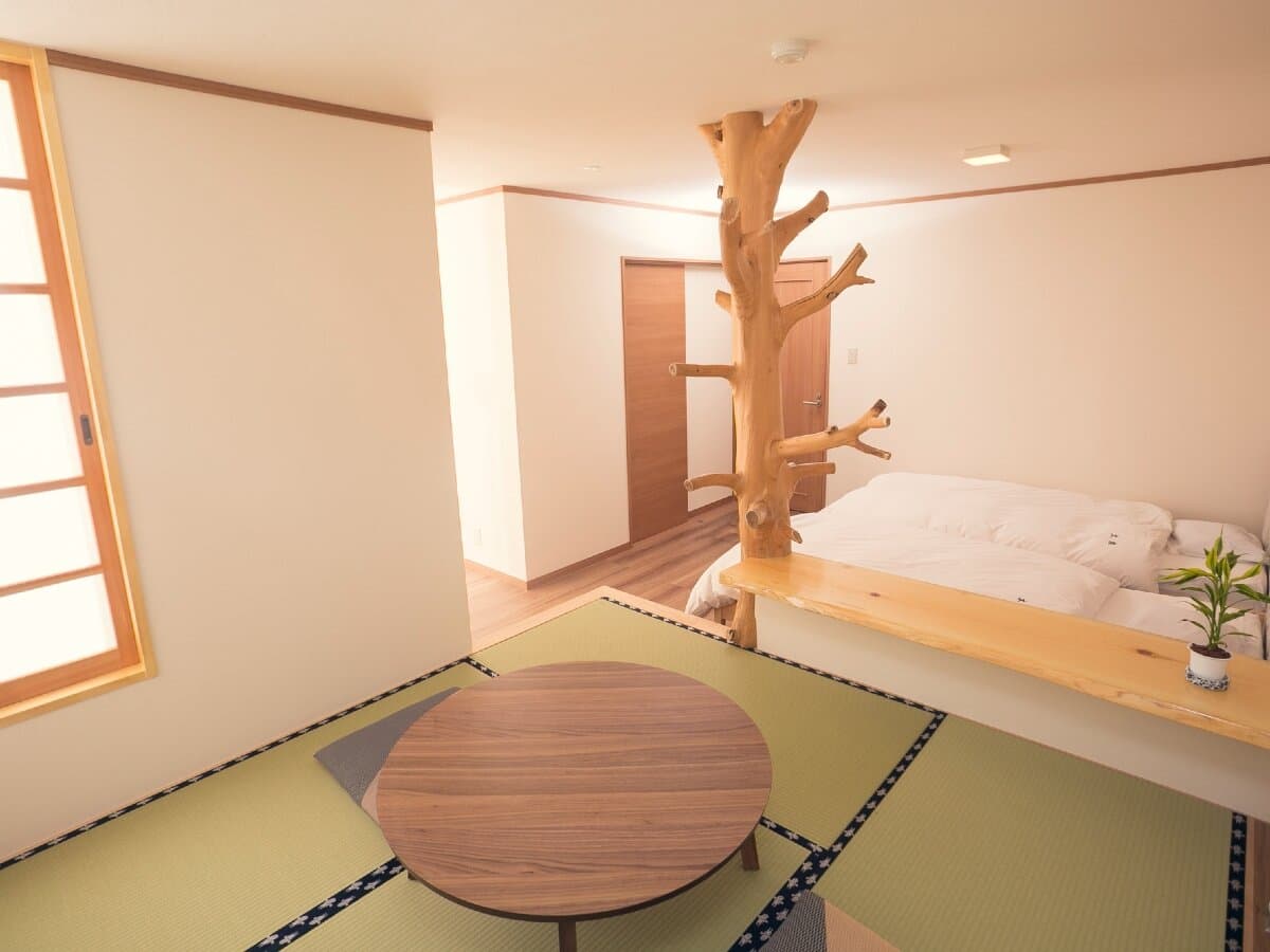 Guest room at Ryokan Mokuzin blending tatami floor with a low bed and a sculptural natural-wood pillar