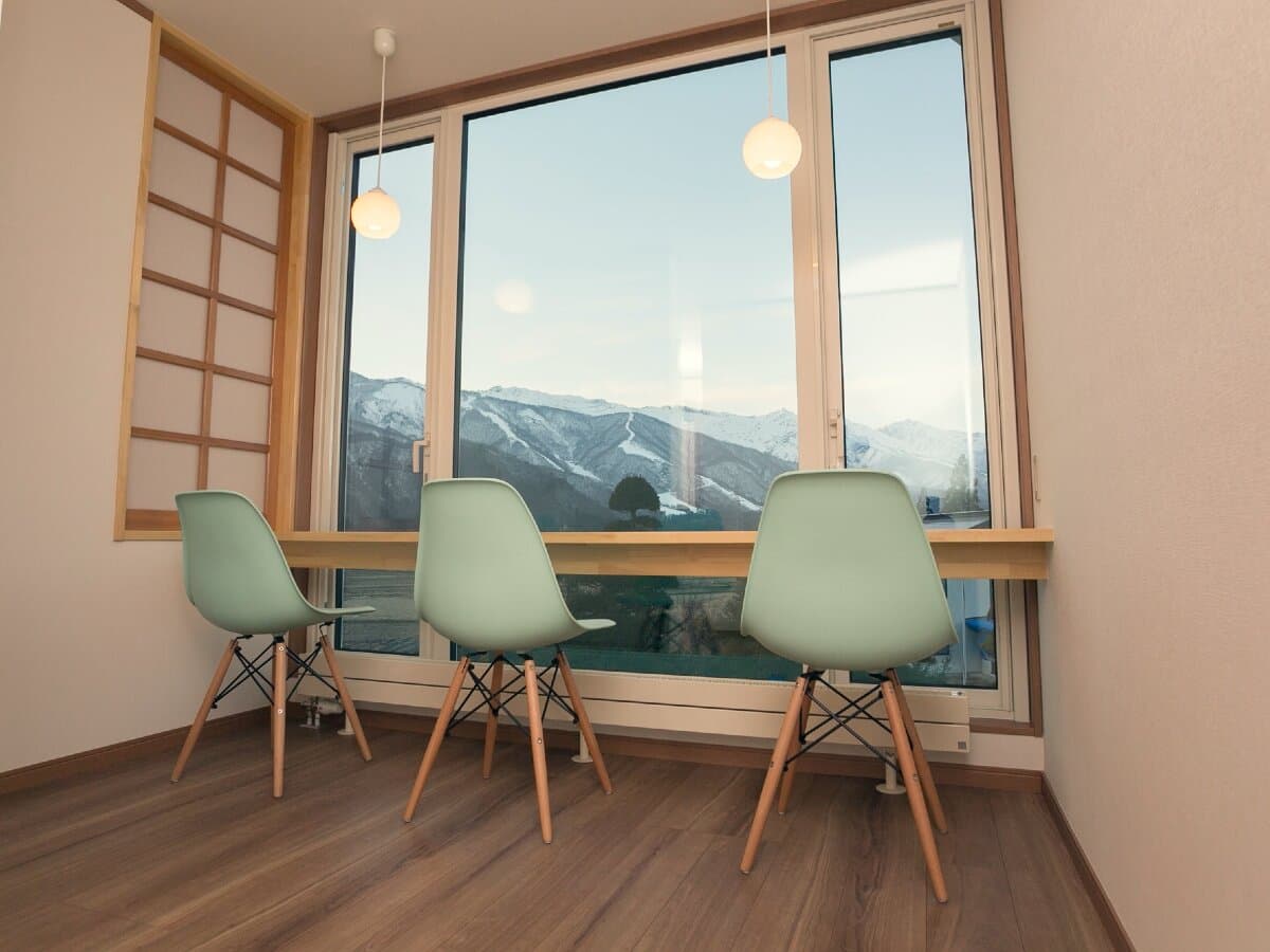 Lounge corner at Ryokan Mokuzin with chairs facing a window framing the snow-capped Hakuba mountains