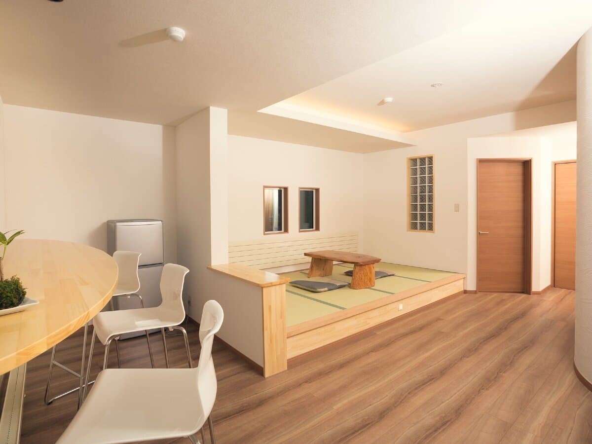 Spacious guest room at Ryokan Mokuzin with a raised tatami sitting area, low table and dining nook