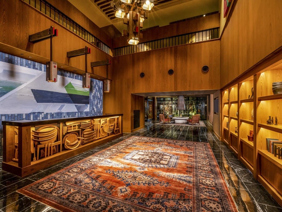 Double-height lobby at Mercure Hida Takayama with warm cedar walls, a large Persian rug and craft-wood reception