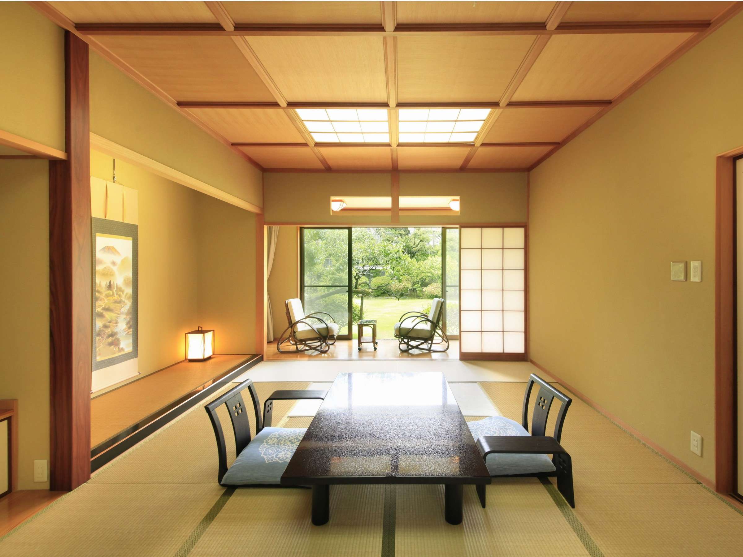Spacious tatami guest room with tokonoma alcove and chairs facing the green garden at Hotel Dankoen, Ito Onsen, Izu