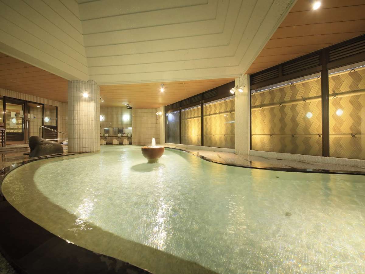 Large indoor onsen bath with central fountain and tiled walls at Hotel Dankoen, Ito Onsen, Izu
