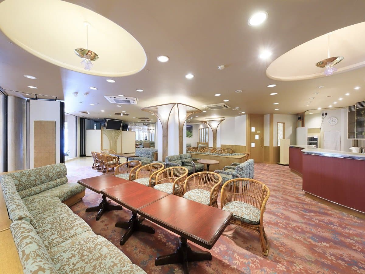 Spacious lobby lounge with rattan armchairs and floral sofas near reception at Hotel Dankoen, Ito Onsen