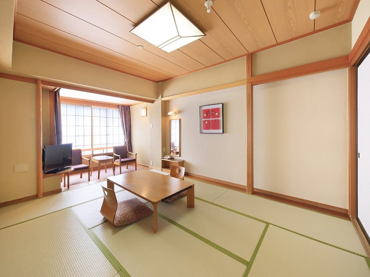 Traditional Japanese tatami room with low table and garden-view sitting area at Hotel Dankoen, Ito Onsen