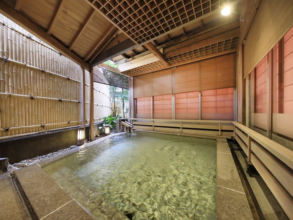 Outdoor rotenburo hot spring bath enclosed by bamboo fencing and lanterns at Hotel Dankoen, Ito Onsen, Izu