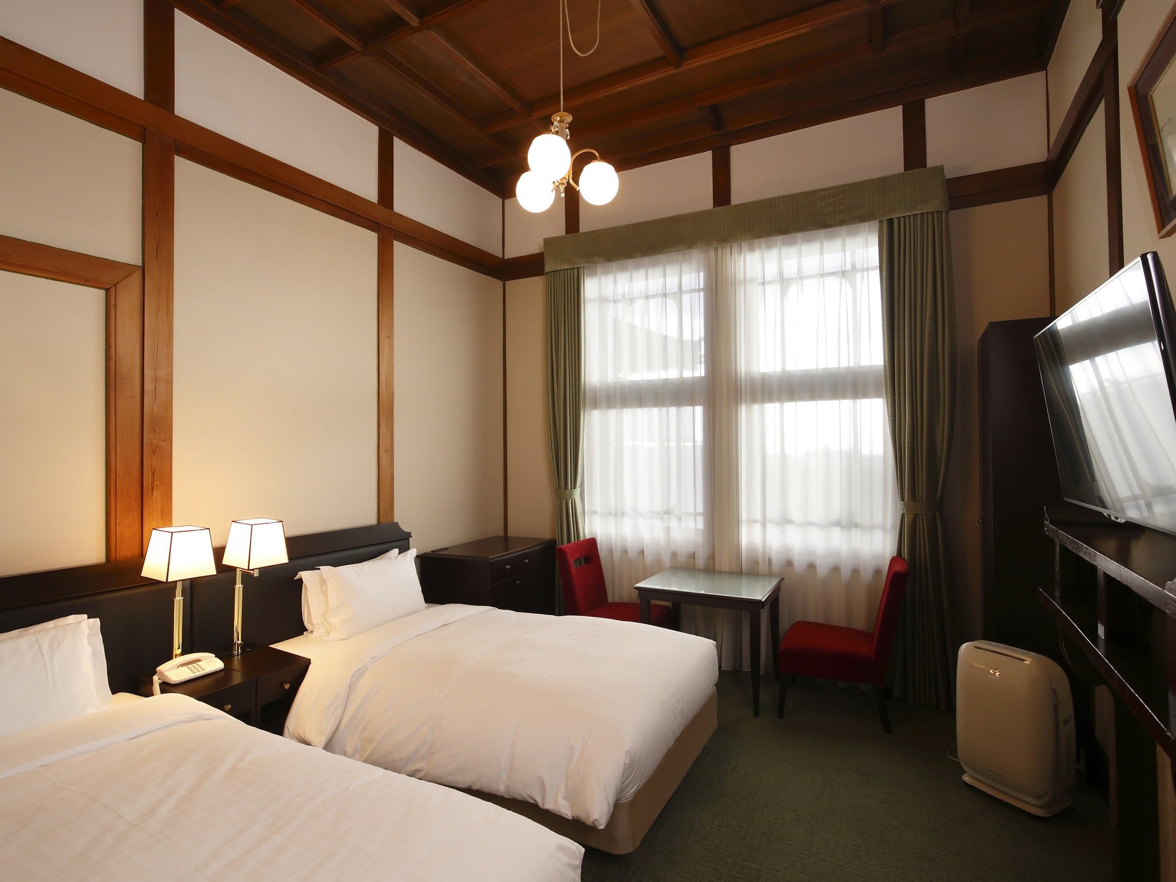 Classic twin guest room at Nara Hotel with coffered wood ceiling, antique lamps and green carpet