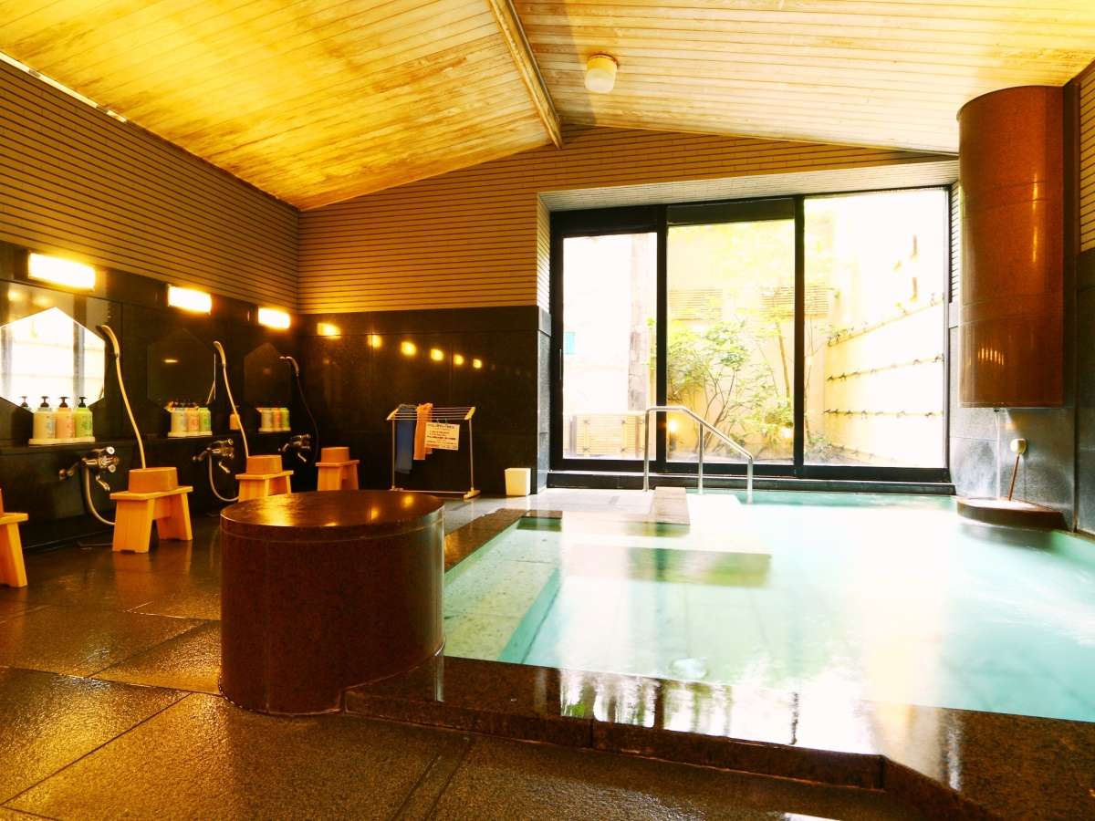 Indoor hot-spring bath with wooden ceiling, wash stations and garden window at Oyado Yamashita, Yuwaku Onsen