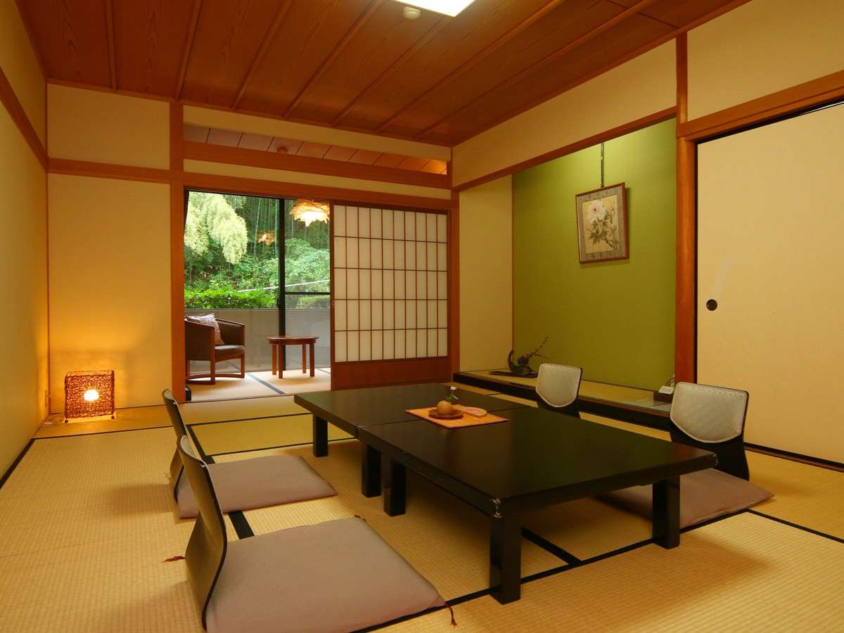Tatami guest room with lacquered table and forest view through a wide window at Oyado Yamashita, Yuwaku Onsen