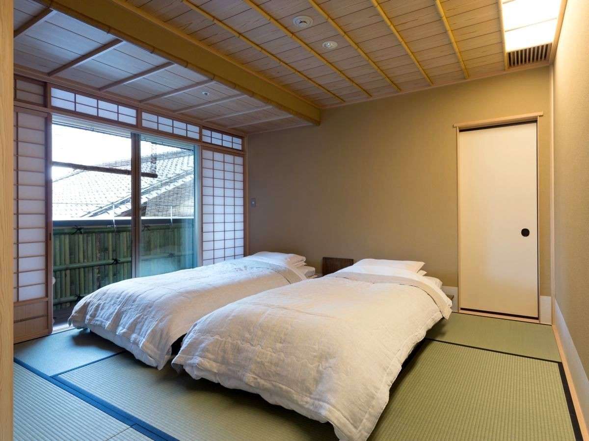 Western-style guest bedroom with low double bed and garden view at Kinjohro ryokan in Kanazawa
