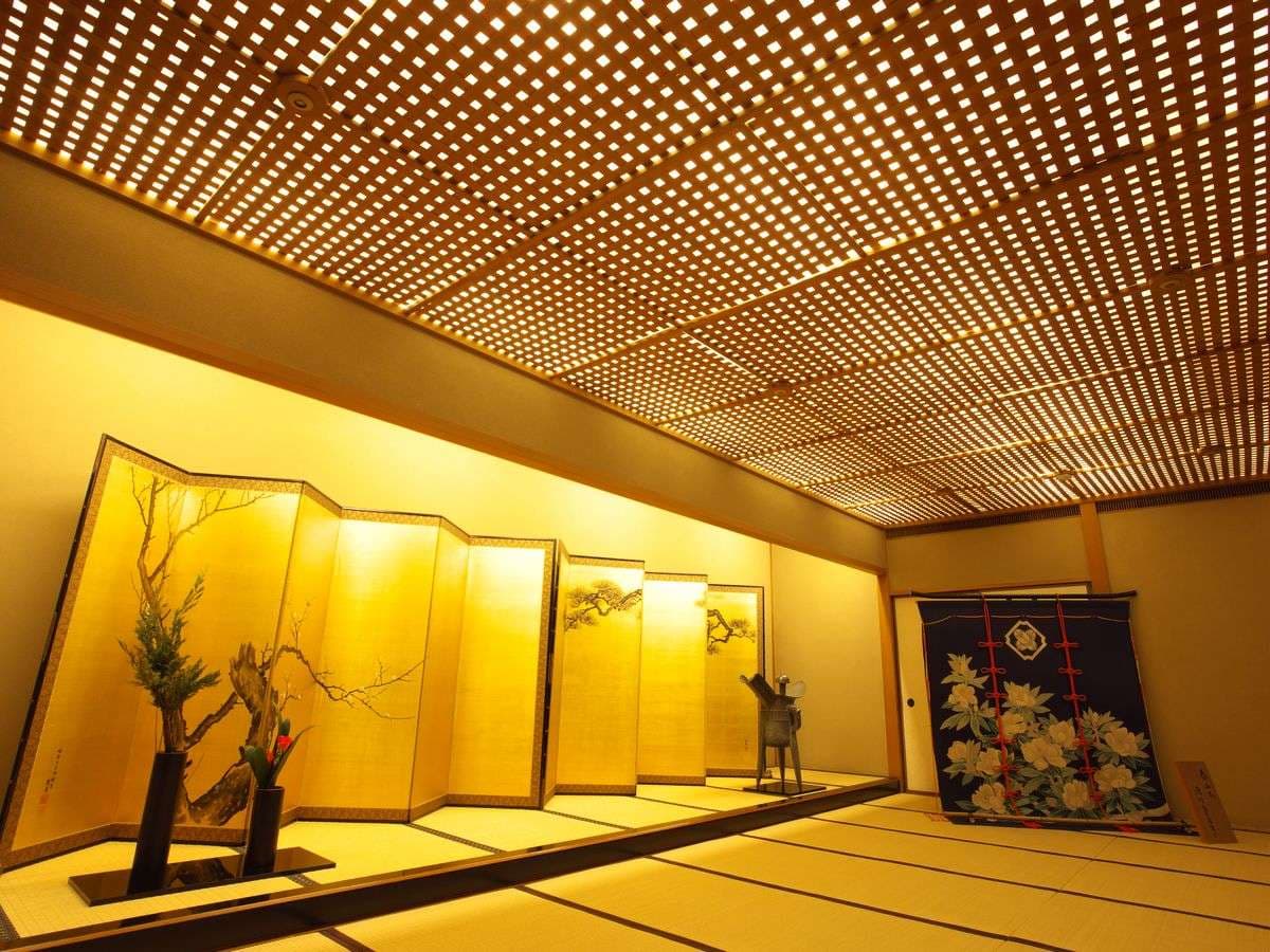 Softly lit lounge corridor with seating and ikebana display at Kinjohro in Kanazawa