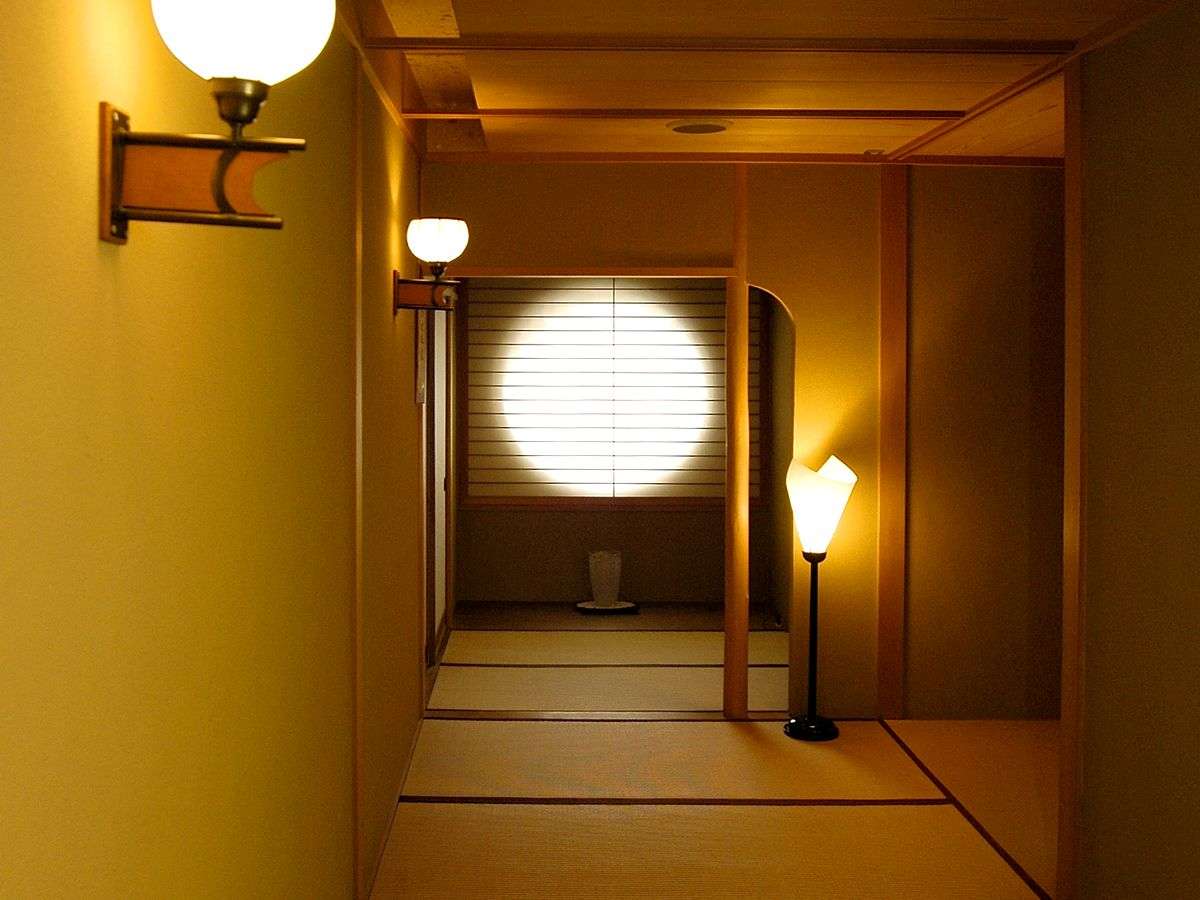 Traditional corridor with round moon window and hanging lanterns at Kinjohro in Kanazawa