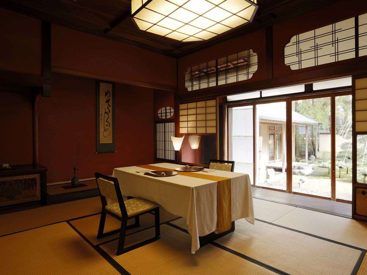 Spacious tatami guest room with low table and garden-facing windows at Kinjohro in Kanazawa