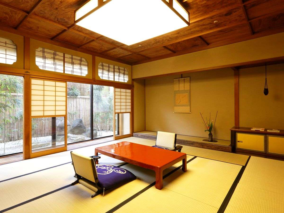 Traditional tatami room with red lacquer table and views of the garden at Kinjohro, Kanazawa