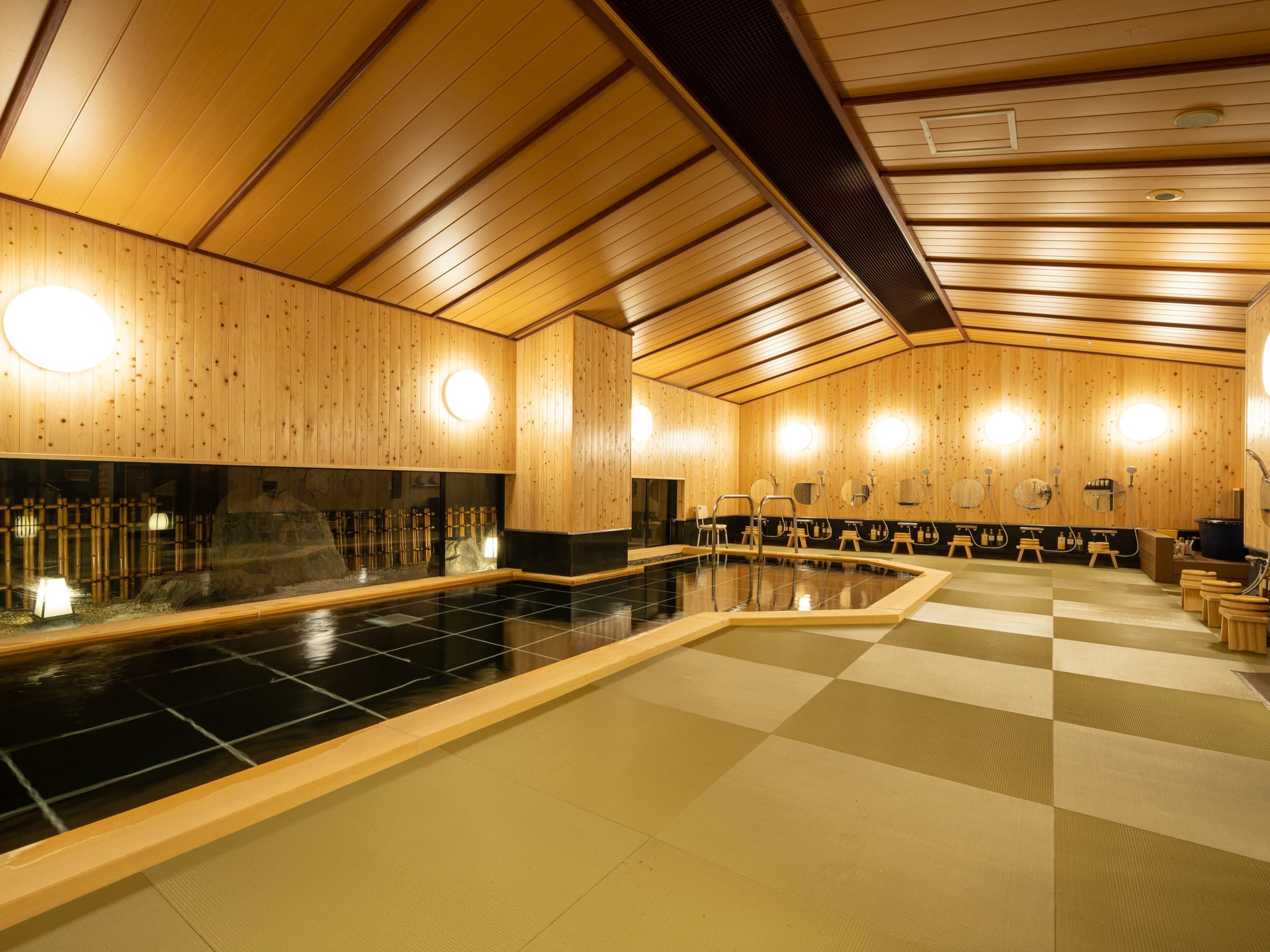 Large cypress-walled indoor public bath at Hida Hotel Plaza in Takayama Onsen, softly lit at evening