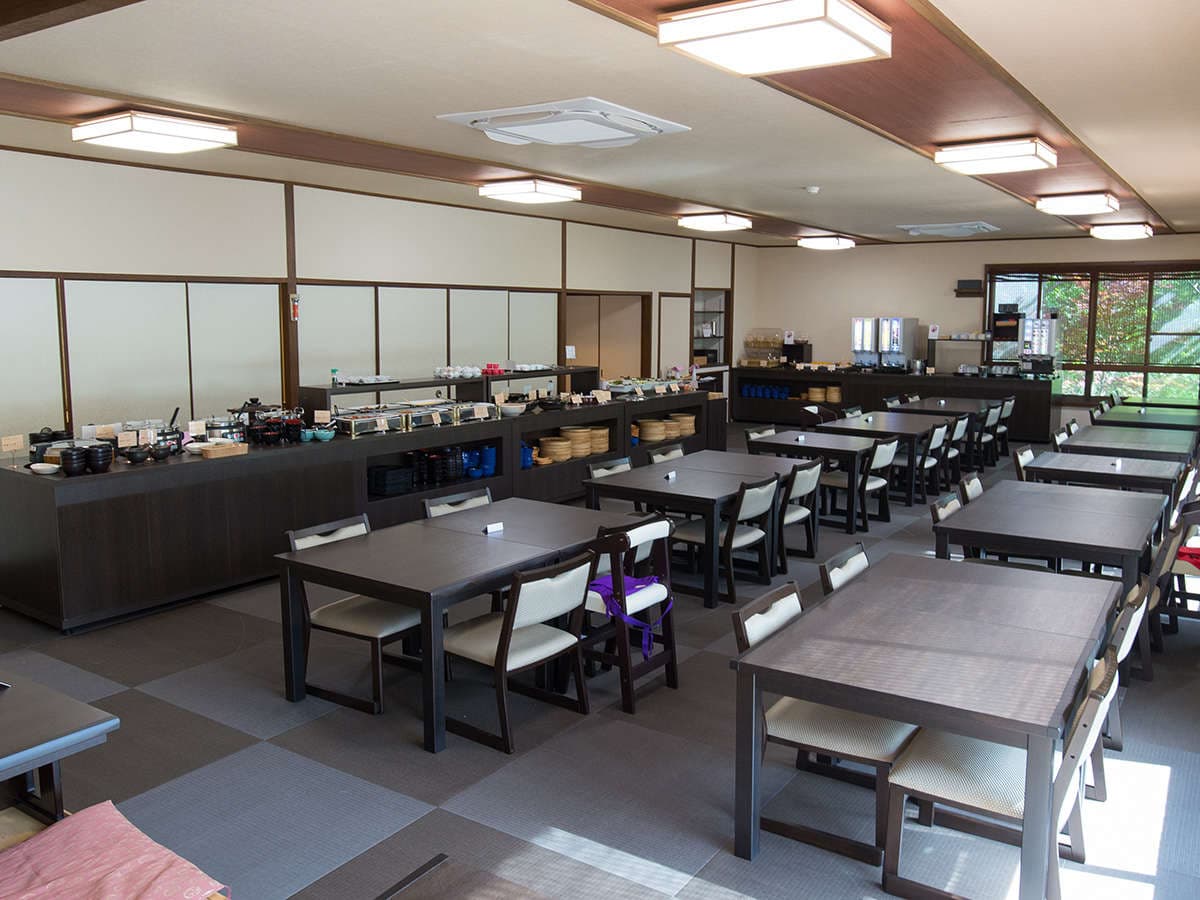 Spacious in-house dining hall with dark wooden tables, buffet counter and garden-view windows at Motoyu Ryusenkaku, Arima Onsen
