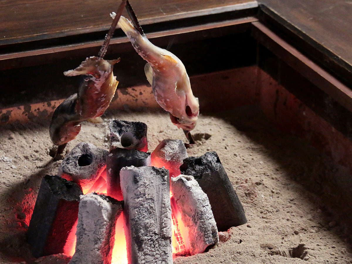 River fish skewered and grilled over glowing charcoal in an irori hearth at Ryokan Murayama