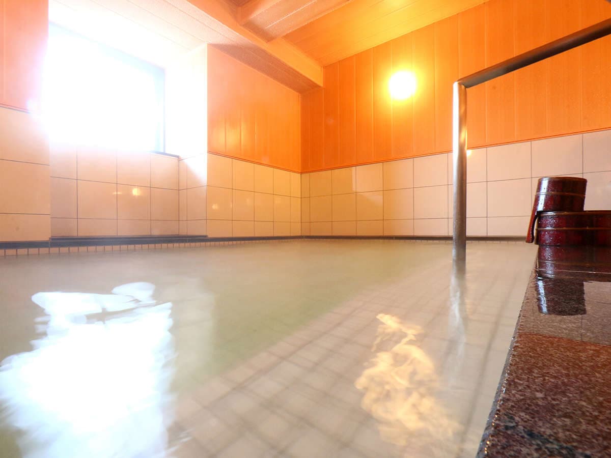 Spacious tiled indoor onsen bath at Ryokan Murayama lit by a corner window in Takayama