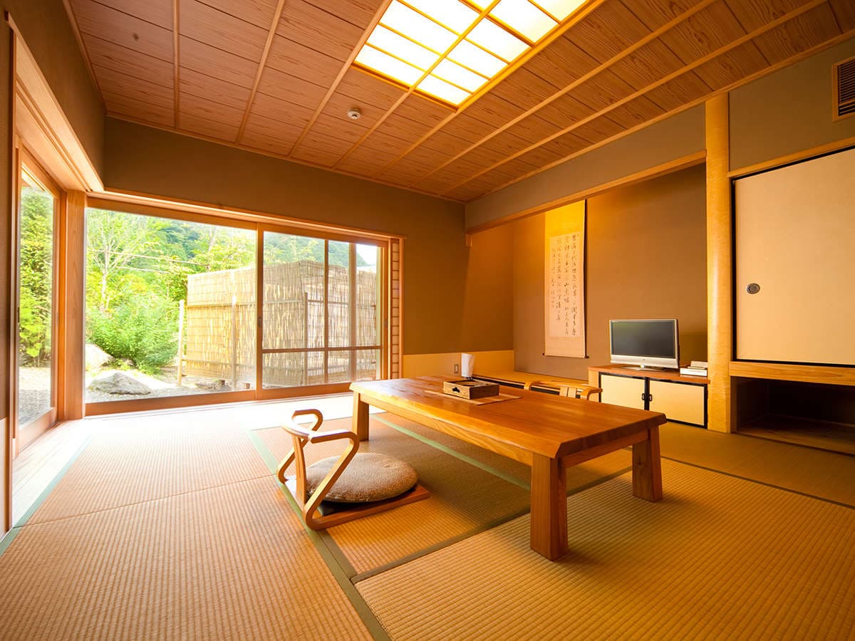 Sunlit tatami guest room at Yufuin Hoteiya with floor table and sliding doors framing a private garden