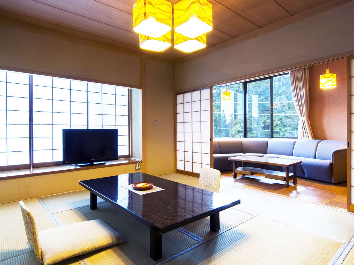 Japanese-style guest room with low lacquer table, floor cushions and a separate sofa lounge area at Hotel Seikoen