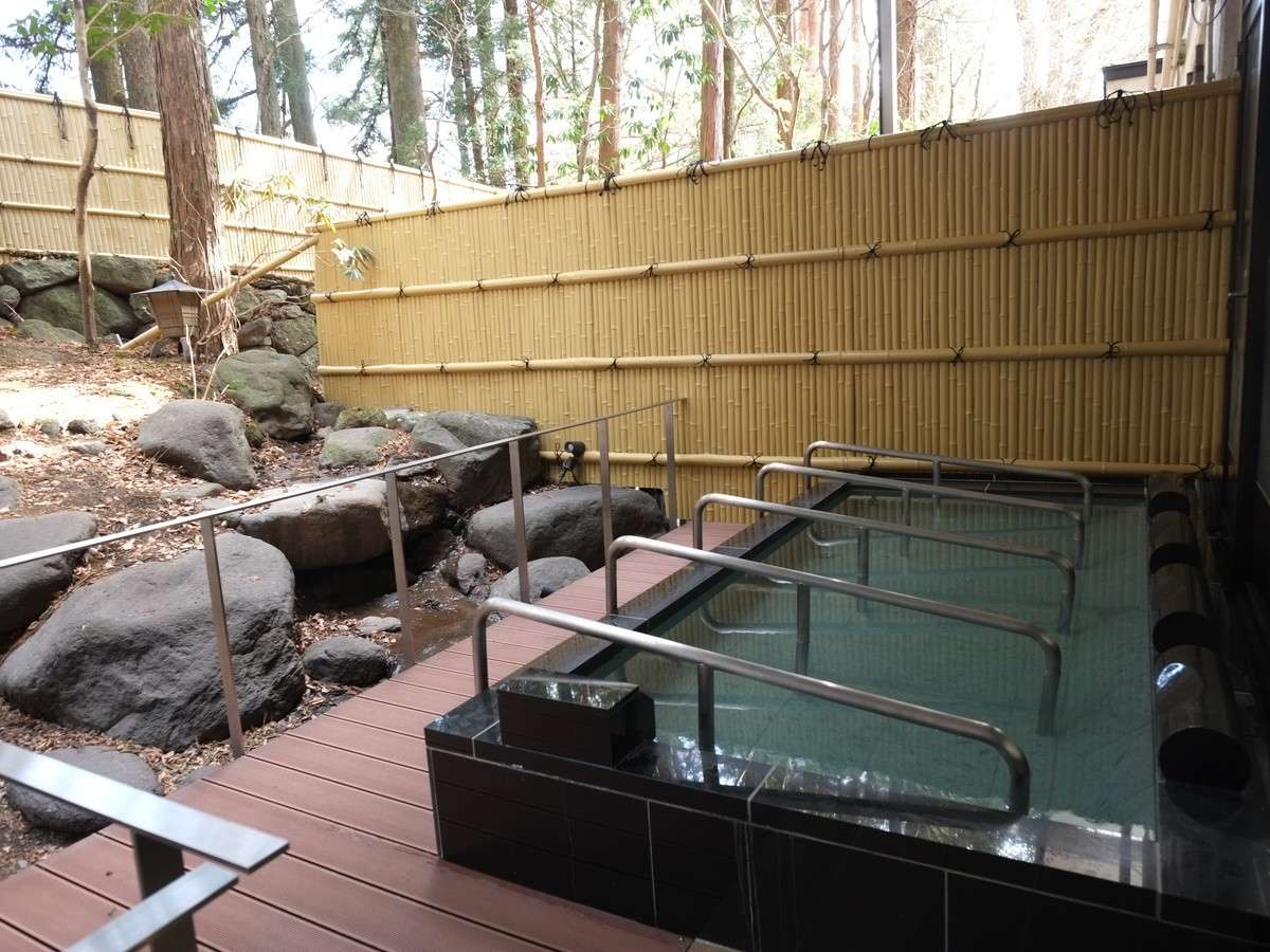 Private open-air rotenburo bath on a wooden deck enclosed by bamboo fencing and natural rocks at Hotel Seikoen