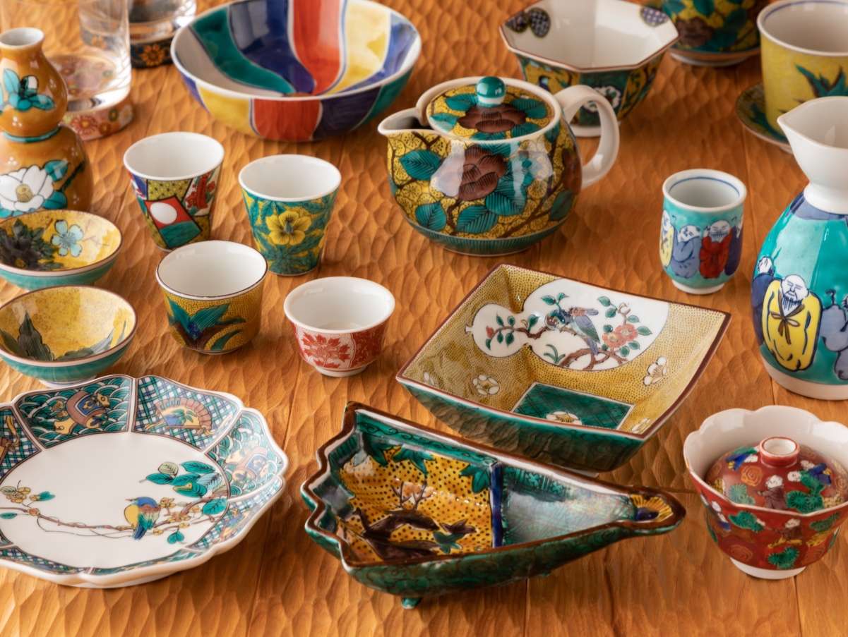 Colorful Kanazawa Kutani-ware cups, teapots and plates arranged on a wooden table at Yunode Ryokan