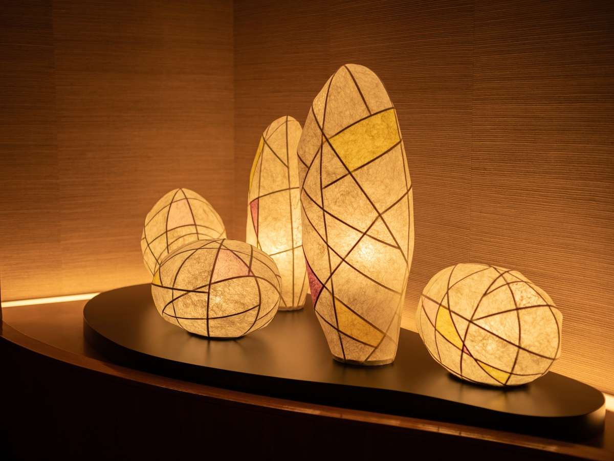 Glowing handmade washi paper lanterns displayed on a low stage in a softly lit alcove at Yunode Ryokan