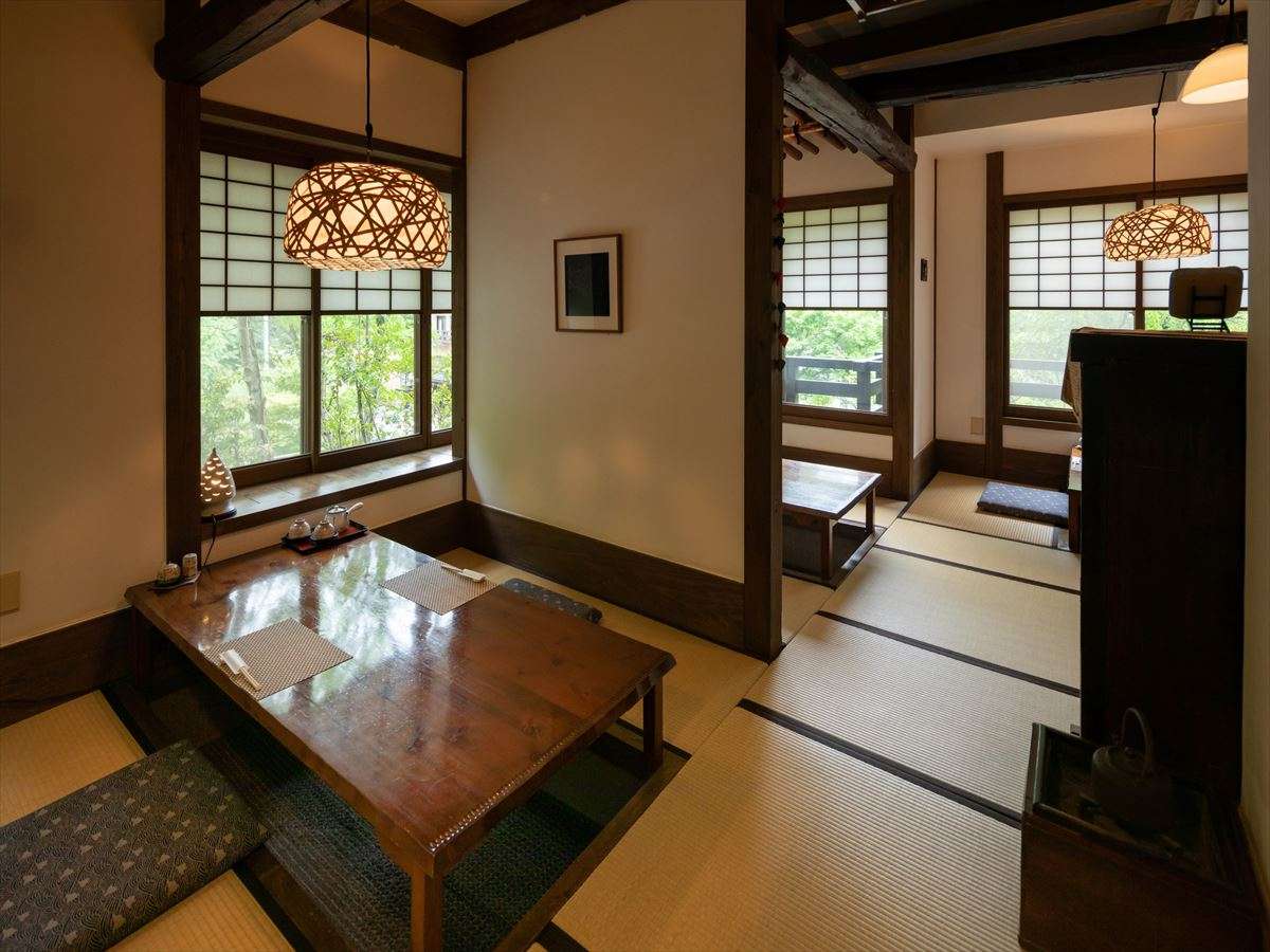 Connected tatami rooms at Fujiya with woven pendant lamps, low lacquer table and shoji windows looking onto greenery