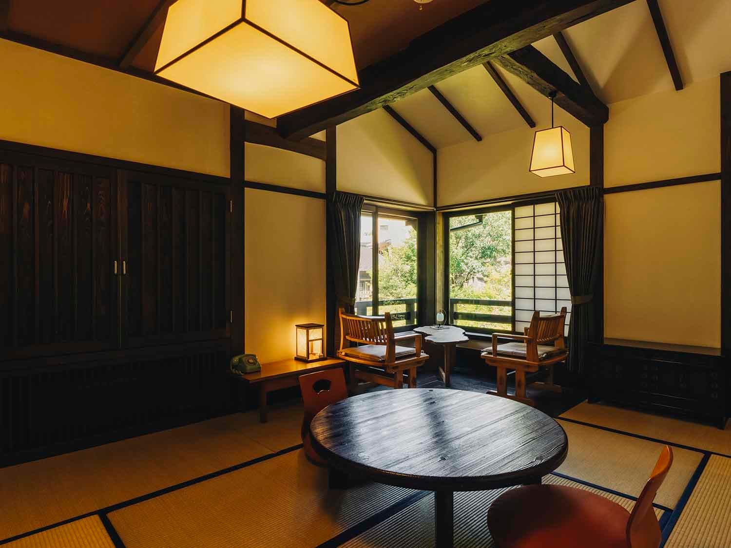 Tatami guest room at Fujiya with a square paper lantern, round table and a wide window framing the forested stream valley
