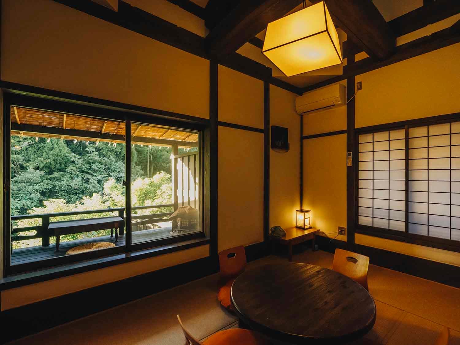 Tatami guest room at Fujiya with exposed dark beams, vaulted ceiling, paper lantern lights and a round low table