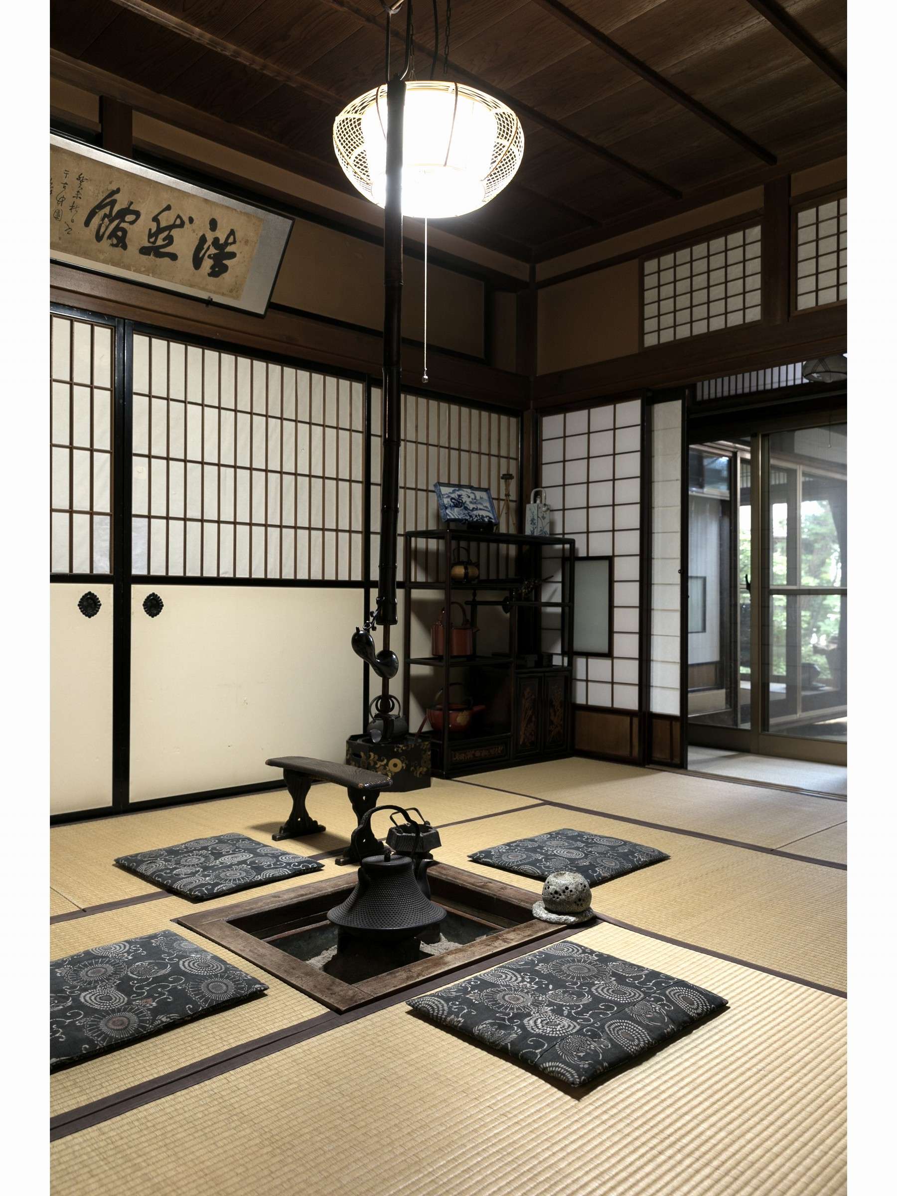 Tatami room with a sunken irori hearth, indigo floor cushions and shoji screens at Sumiyoshi Ryokan, Hida Takayama