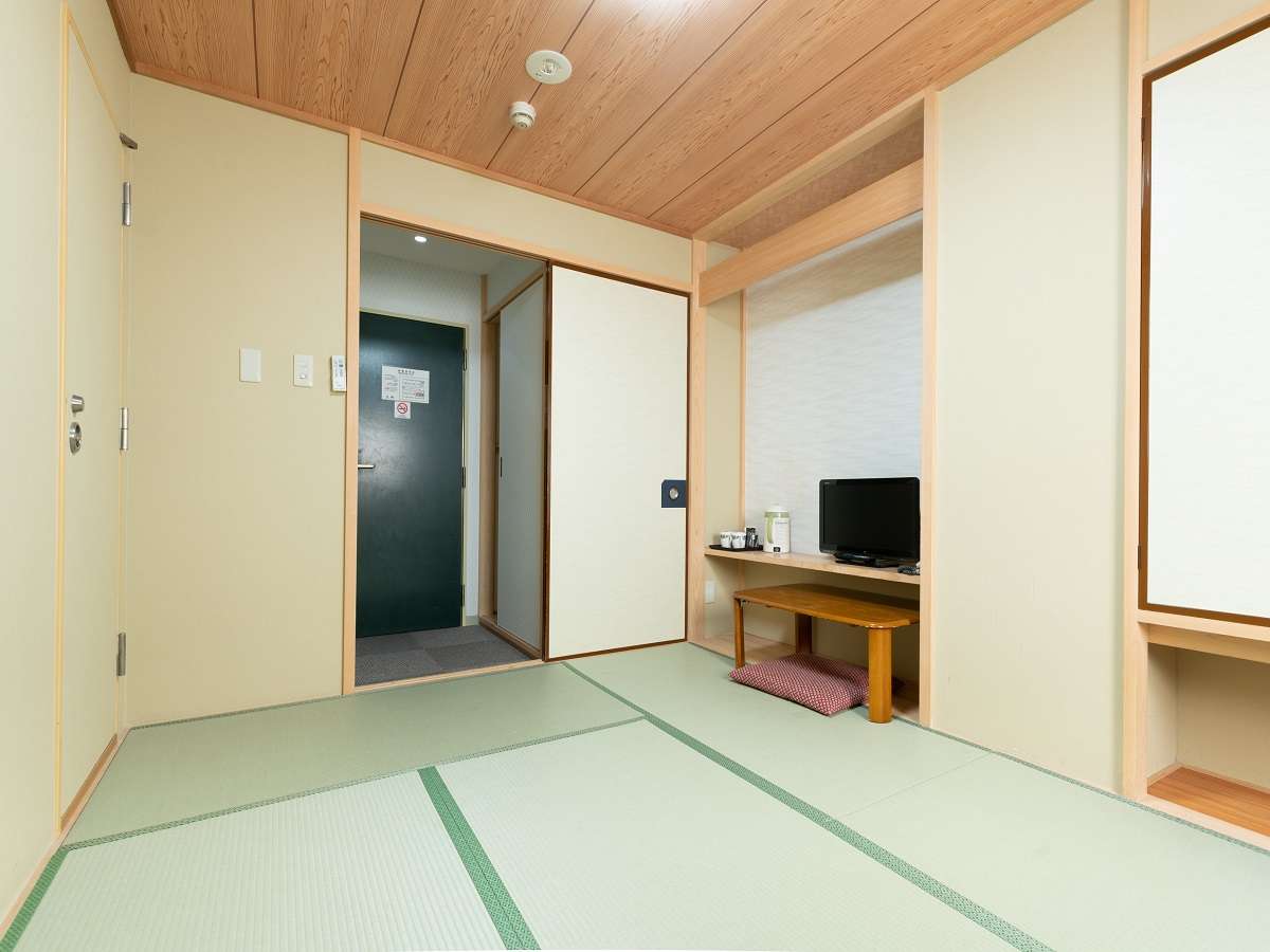 Clean tatami guest room at Sakura Ryokan with wood-panel ceiling and recessed shelf nook