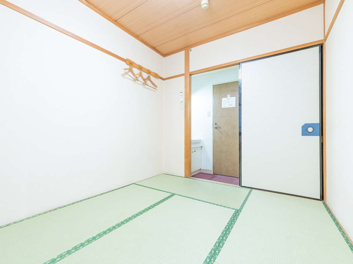 Compact tatami guest room at Sakura Ryokan with hanging coat rack and entryway with washbasin