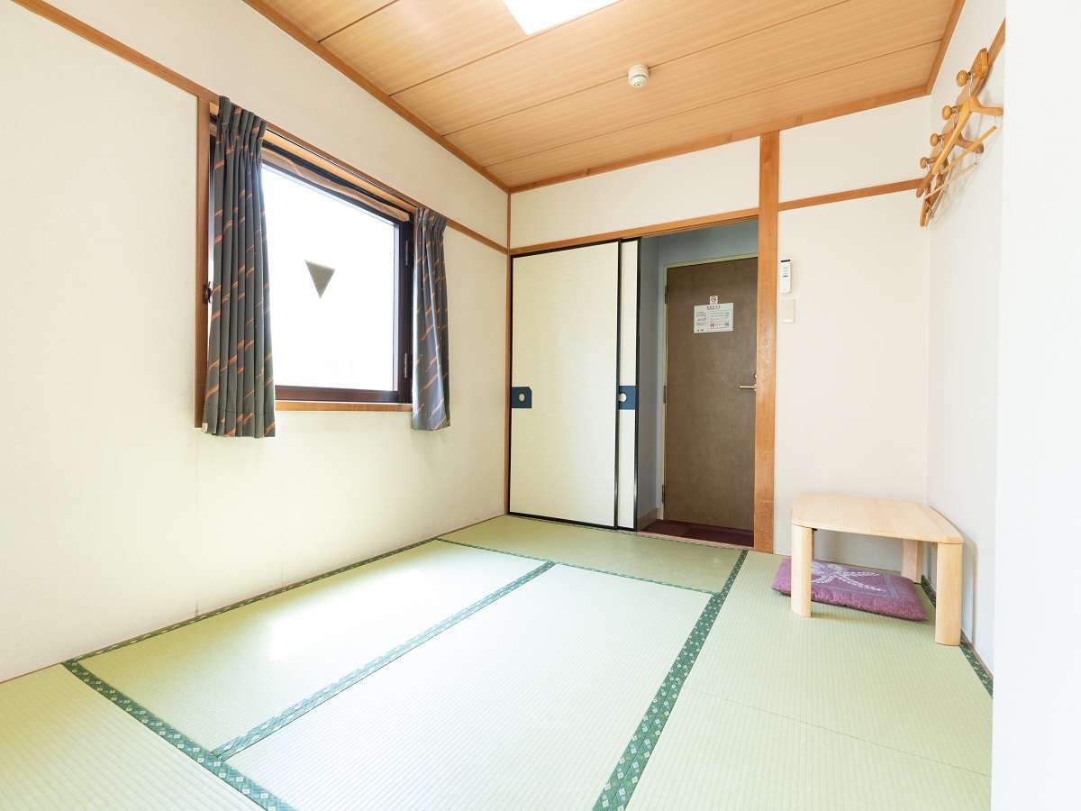 Corner tatami guest room at Sakura Ryokan with bay window, coat rack and floor cushion seating