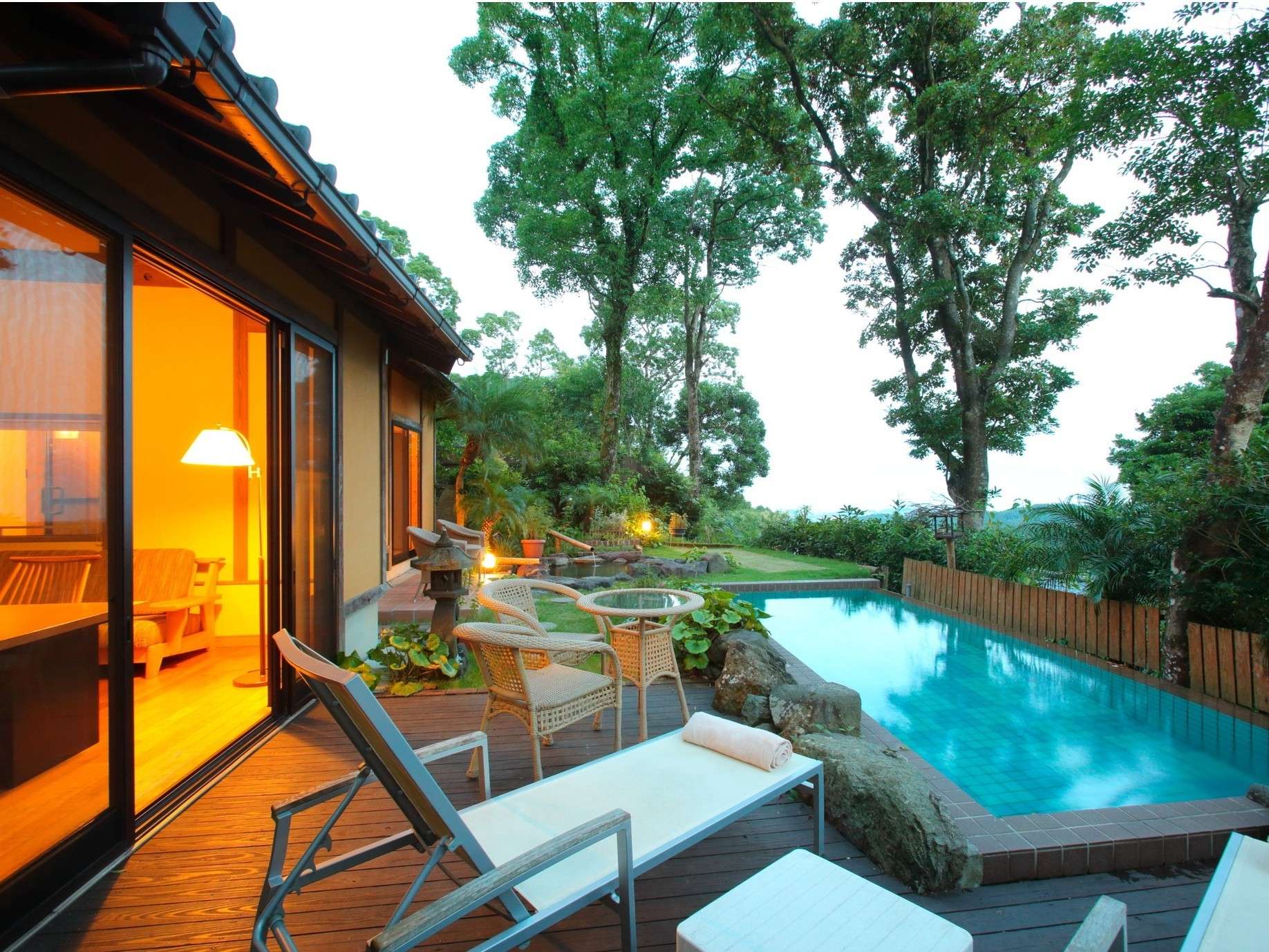 Private infinity hot-spring pool and deck loungers beside a softly lit villa room at Yurian at dusk, Ibusuki Onsen